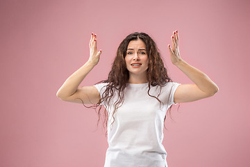 Image showing Beautiful female half-length portrait isolated on pink studio backgroud. The young emotional surprised woman