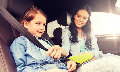 Image showing happy woman fastening child with seat belt in car
