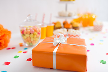 Image showing birthday present in orange wrap on table at party