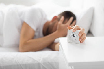 Image showing close up of man in bed reaching for alarm clock