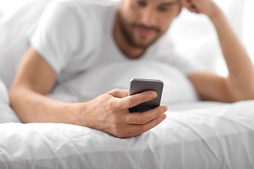 Image showing close up of man with smartphone in bed in morning