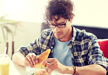 Image showing happy man eating sandwich at cafe for lunch