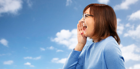 Image showing senior woman in glasses calling over sky