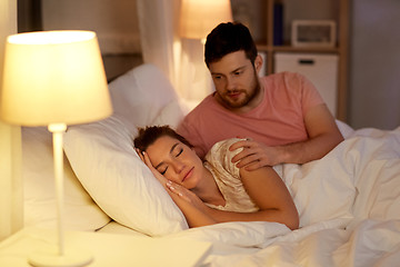 Image showing man waking his sleeping wife up in bed at home