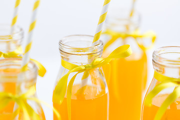 Image showing orange juice in glass bottles with paper straws