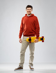 Image showing smiling young man in hoodie with short skateboard