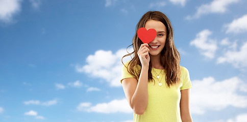 Image showing smiling teenage girl covering her eye by red heart