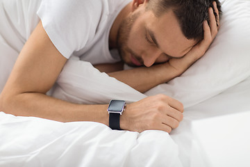 Image showing close up of man with smart watch sleeping in bed