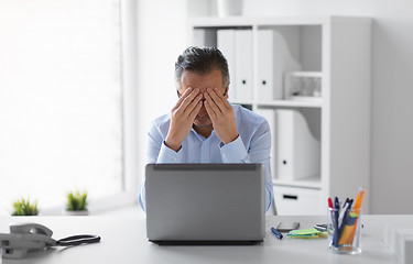 Image showing stressed businessman with laptop working at office