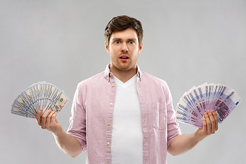 Image showing confused young man with euro and dollar money