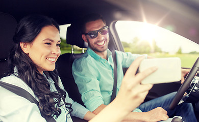 Image showing happy couple in car taking selfie with smartphone