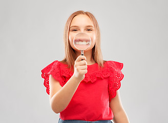 Image showing happy girl with magnifying glass over her teeth