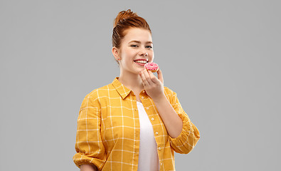 Image showing smiling red haired teenage girl eating donut