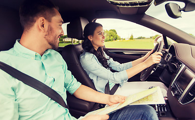 Image showing happy man and woman with road map driving in car