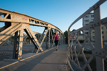 Image showing woman jogging across the bridge at sunny morning