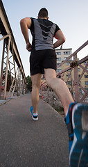 Image showing man jogging across the bridge at sunny morning