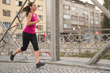 Image showing woman jogging across the bridge at sunny morning