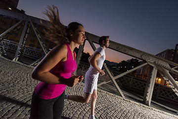 Image showing couple jogging across the bridge in the city