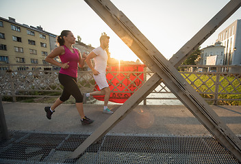 Image showing young couple jogging across the bridge in the city