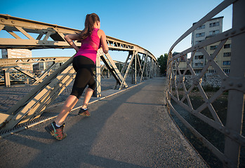 Image showing woman jogging across the bridge at sunny morning