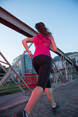 Image showing woman jogging across the bridge at sunny morning