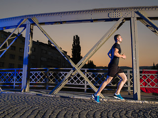 Image showing man jogging across the bridge in the city