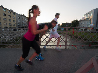 Image showing group of young people jogging across the bridge