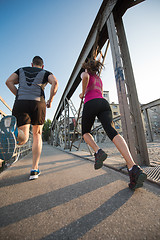 Image showing young couple jogging across the bridge in the city