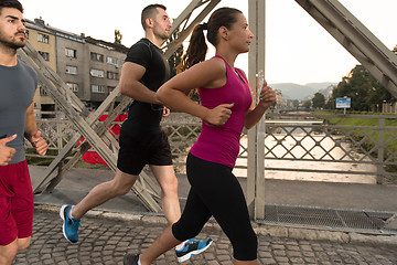 Image showing group of young people jogging across the bridge