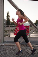 Image showing woman jogging across the bridge at sunny morning