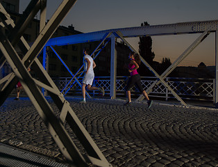 Image showing portrait of couple jogging across the bridge in the city