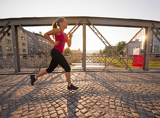 Image showing woman jogging across the bridge at sunny morning