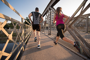 Image showing young couple jogging across the bridge in the city