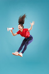 Image showing Beautiful young woman jumping with megaphone isolated over red background