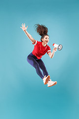 Image showing Beautiful young woman jumping with megaphone isolated over red background