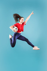 Image showing Forward to the victory.The young woman as soccer football player jumping and kicking the ball at studio on pink