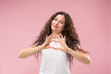 Image showing The happy business woman standing and smiling against pink background.