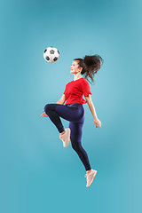 Image showing Forward to the victory.The young woman as soccer football player jumping and kicking the ball at studio on pink