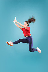 Image showing Image of young woman over pink background using laptop computer or tablet gadget while jumping.