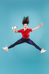 Image showing Beautiful young woman jumping with megaphone isolated over red background