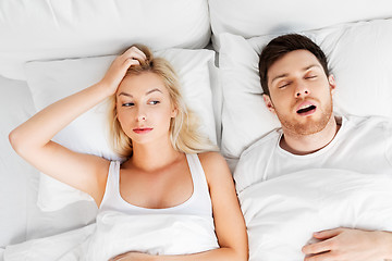 Image showing unhappy woman in bed with snoring sleeping man