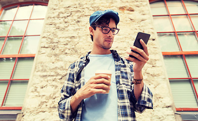 Image showing man with smartphone drinking coffee on city street