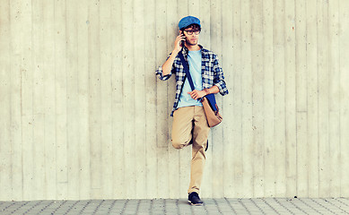 Image showing man with bag calling on smartphone at street wall