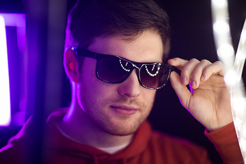 Image showing man in sunglasses over ultra violet neon lights