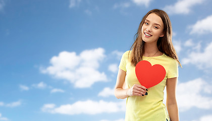 Image showing smiling teenage girl with red heart over sky