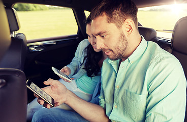 Image showing couple with smartphones riding on back seat of car