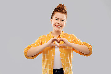 Image showing smiling red haired teenage girl making hand heart