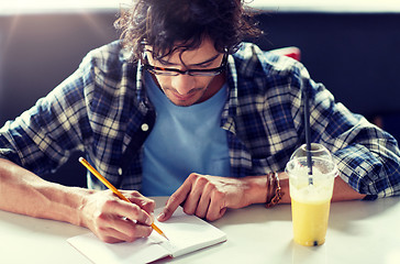 Image showing man with notebook and juice writing at cafe