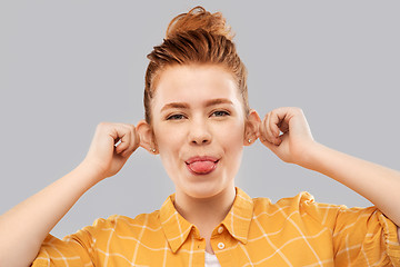 Image showing smiling red haired teenage girl showing her tongue