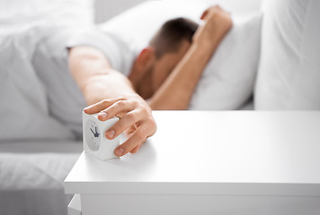 Image showing close up of man in bed reaching for alarm clock